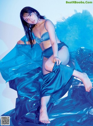 A woman in a blue dress sitting on a blue chair.