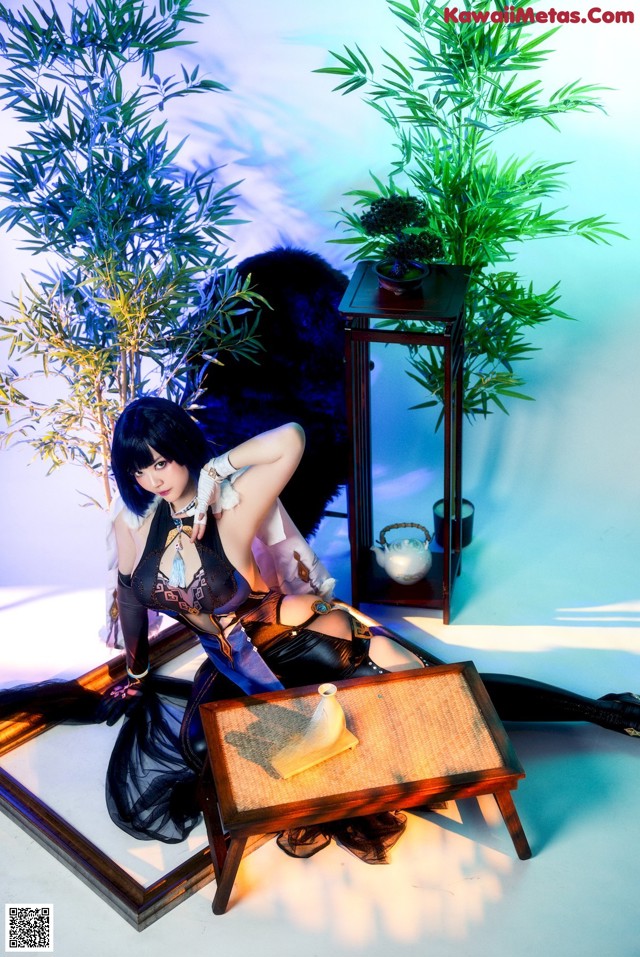 A woman sitting on top of a table next to a plant.