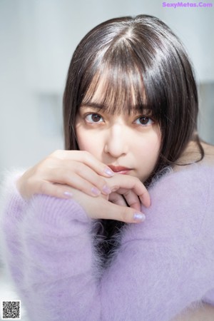 A woman sitting on a couch with her hand on her chin.