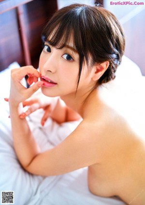 A naked asian woman laying on a bed.