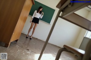 A woman leaning over a desk in a classroom.