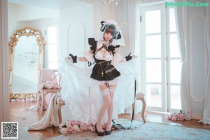 A woman in a maid outfit sitting on a bed.