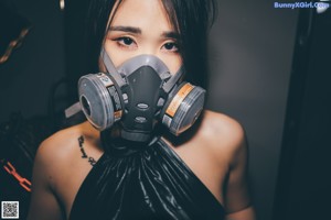 A woman wearing a gas mask sitting on a couch.
