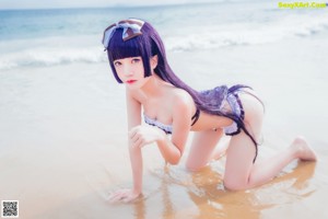 A woman in a bikini sitting on the beach with an inflatable ring.