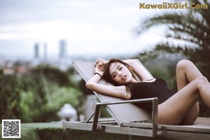 A woman in a gray bikini leaning against a wall.