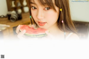 A woman sitting on a wooden bench holding a glass of watermelon.