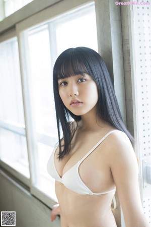 A woman in a white bra top and plaid skirt posing for the camera.
