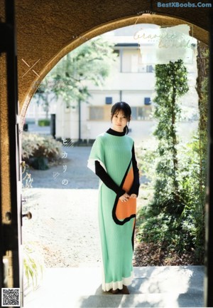 A woman standing in front of an archway wearing a green dress.