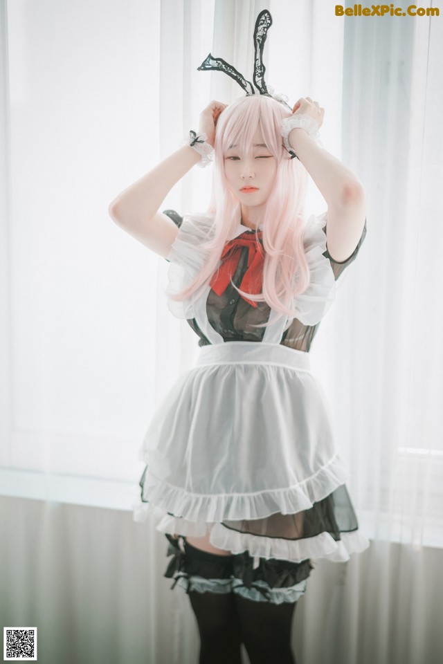 A woman with pink hair wearing a white apron and black stockings.