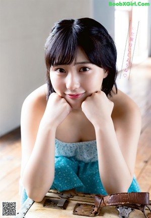 A woman in a blue dress posing on a couch.