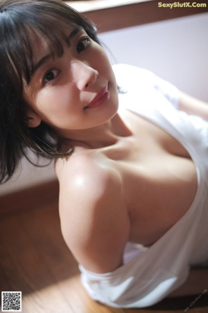 A woman in a white shirt is sitting on the floor.