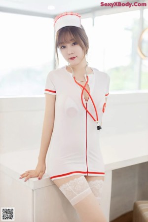 A woman dressed as a nurse holding a remote control.