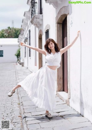 A woman in a white bikini holding a black jacket over her head.