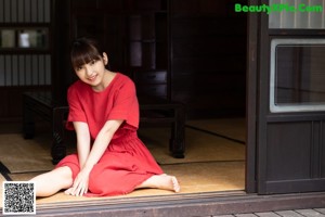 A woman in a red dress walking down a hallway.