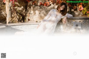 A woman in a white dress sitting in a pool of water.