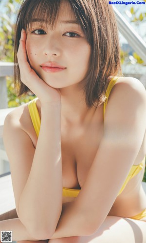 A woman in a white shirt and yellow shorts posing on a balcony.