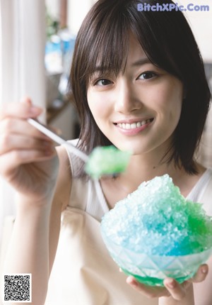 A woman holding a bowl of ice cream in a kitchen.