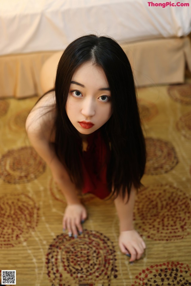 A woman in a red dress is laying on the floor.