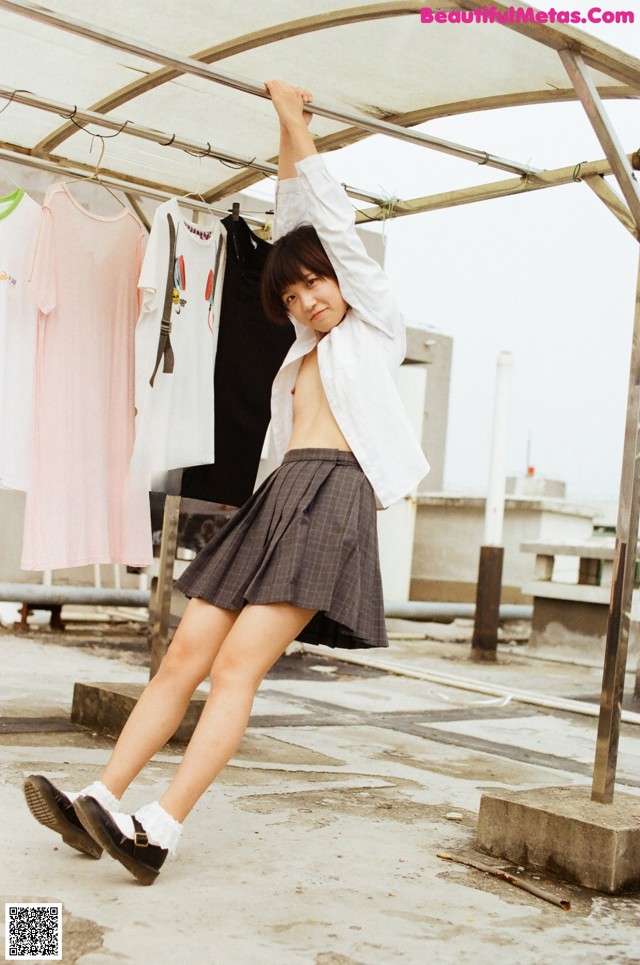 A woman standing on top of a roof next to a rack of clothes.