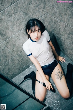 A woman in a white shirt and blue shorts is taking a shower.