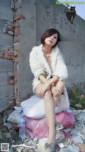 A woman in a white fur coat is posing for the camera.