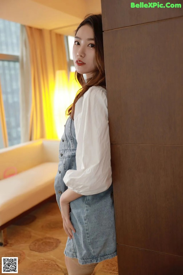 A woman leaning against a wall in a room.