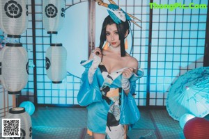 A woman in a blue and white outfit holding a fan.