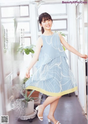 A woman sitting on a wooden bench in a blue dress.