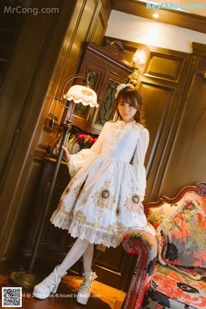 A young girl in a blue and white dress leaning against a door.