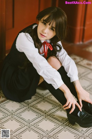 A young girl in a blue and white dress leaning against a door.