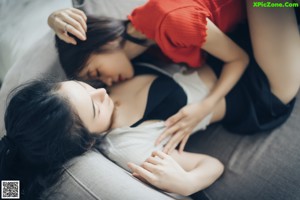 A couple of women sitting on top of a bed.