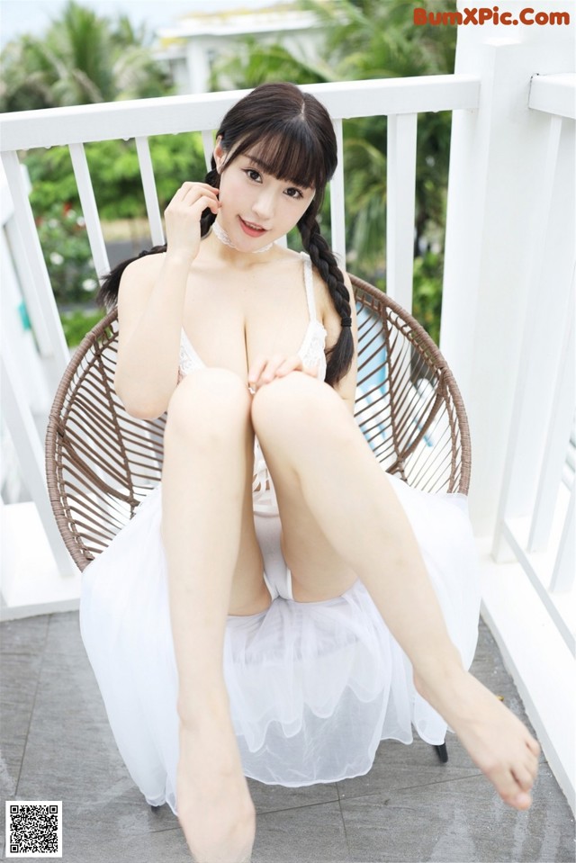 A woman in a white dress sitting on a chair.