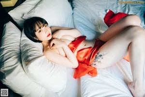 A woman in a red dress laying on a bed.