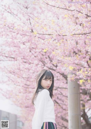 A woman with long black hair wearing a white sweater.